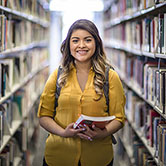 Image Source: CU Digital Asset Management System Student inside the library with a book