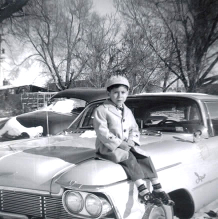 nicely dressed boy sitting on the hood of car