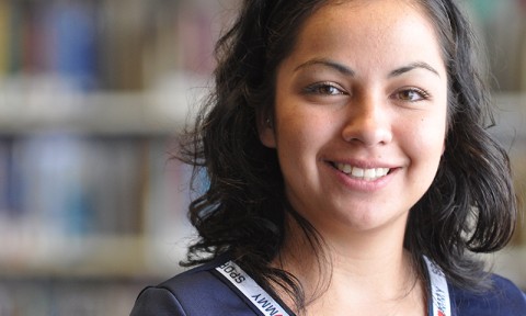 Happy student in front of library book stacks