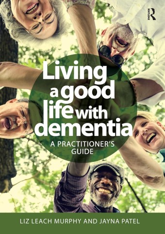 A group of people smiling and holding hands together, surrounded by greenery, showcasing unity and support in a caregiving context.