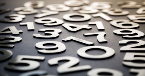 Auraria Library 2024 by the numbers. A cluttered table displaying a disorganized pile of various numbers scattered across its surface. 2024 By The Numbers