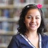 Happy student in front of library book stacks